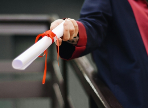 Person in graduation regalia holding diploma