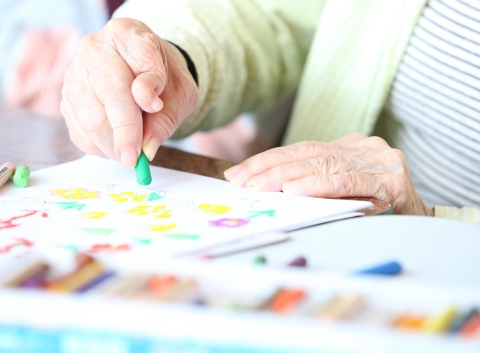 Elderly person drawing in a notebook