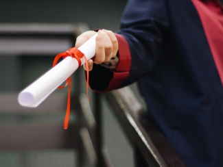 Person in graduation regalia holding diploma
